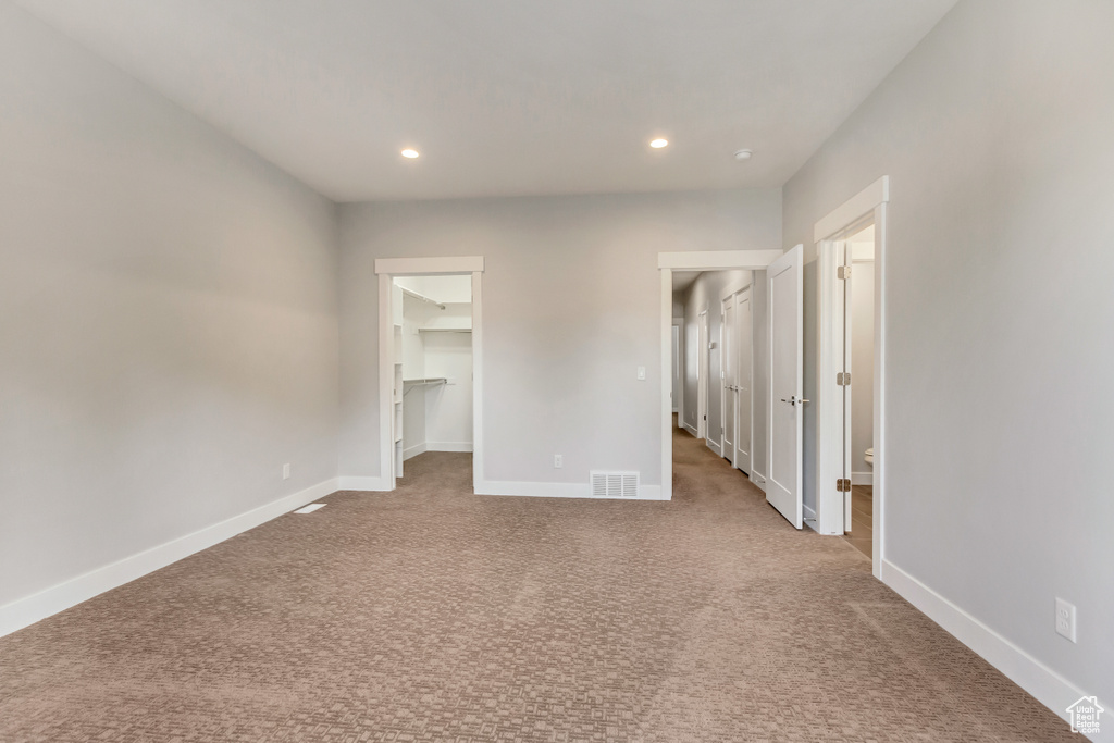 Interior space featuring light carpet, a walk in closet, and a closet