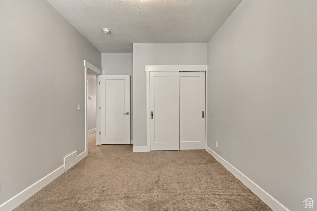 Unfurnished bedroom with light colored carpet and a closet