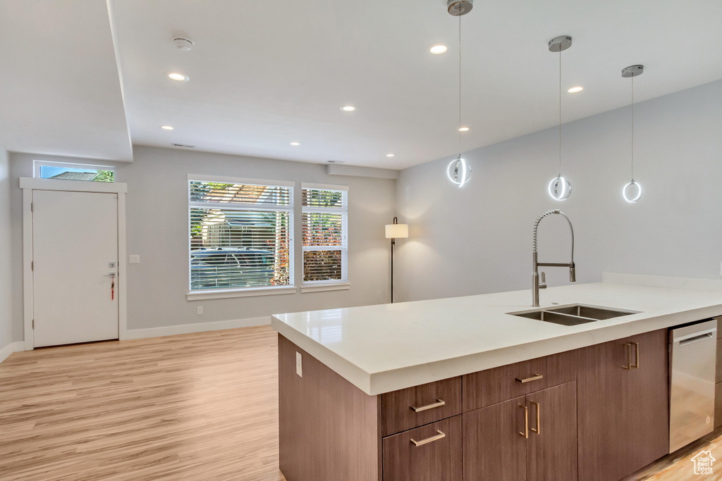 Kitchen with dishwasher, sink, hanging light fixtures, and light hardwood / wood-style floors