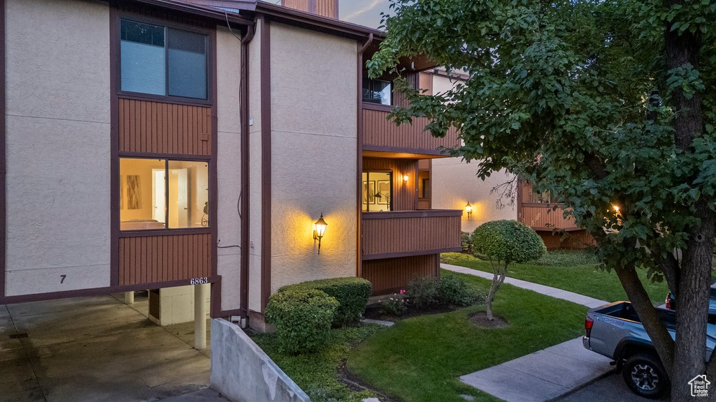 View of side of home featuring a lawn and a balcony