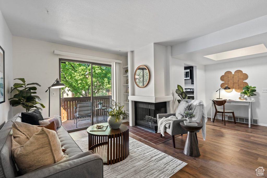 Living room featuring dark wood-type flooring, a multi sided fireplace, and a skylight