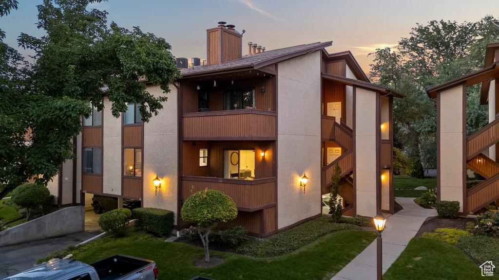 View of front of property featuring a balcony and a lawn