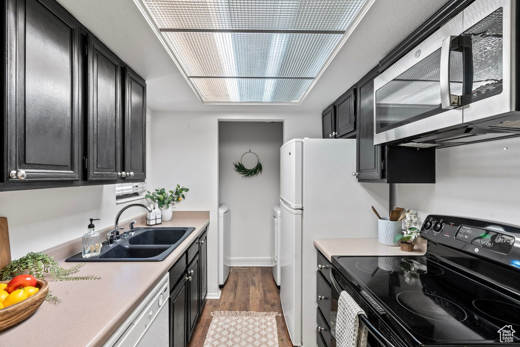 Kitchen featuring dark hardwood / wood-style floors, white dishwasher, independent washer and dryer, sink, and black electric range oven