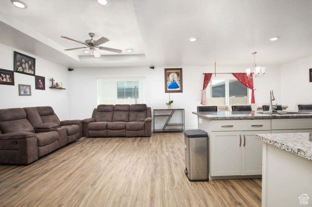 Kitchen with plenty of natural light, sink, ceiling fan with notable chandelier, and light wood-type flooring