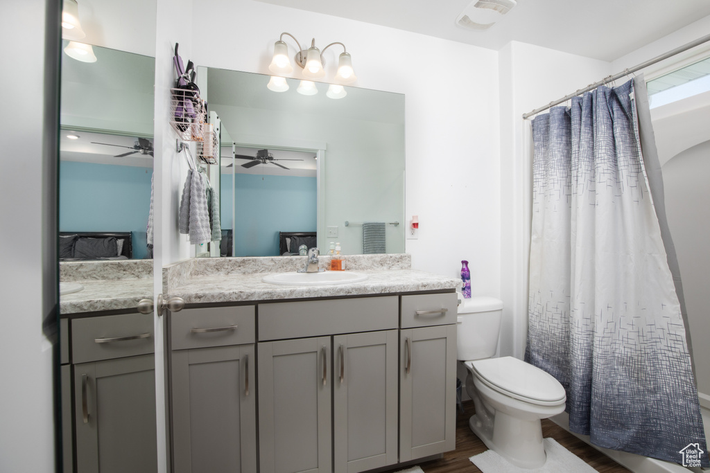 Bathroom featuring vanity, walk in shower, toilet, hardwood / wood-style flooring, and ceiling fan