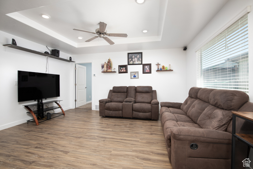 Living room featuring ceiling fan, hardwood / wood-style flooring, and a raised ceiling