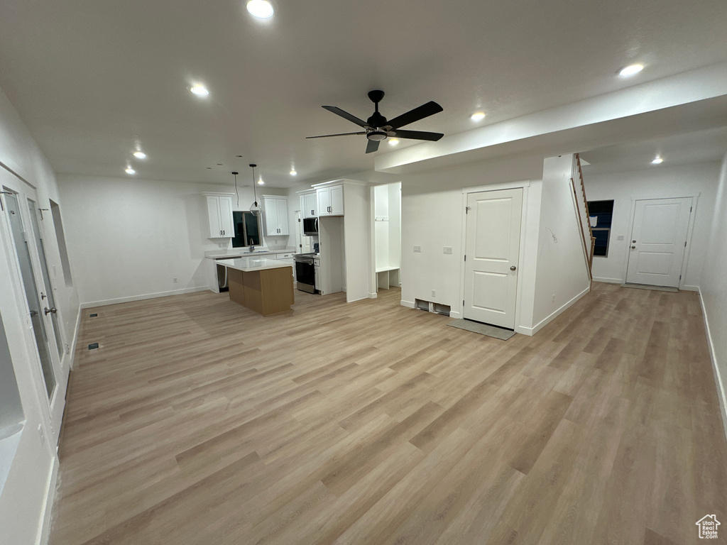 Unfurnished living room with ceiling fan, light wood-type flooring, and sink