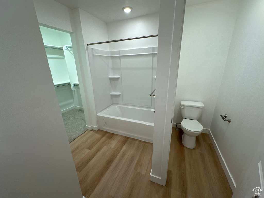 Bathroom featuring wood-type flooring, toilet, and shower / bathing tub combination