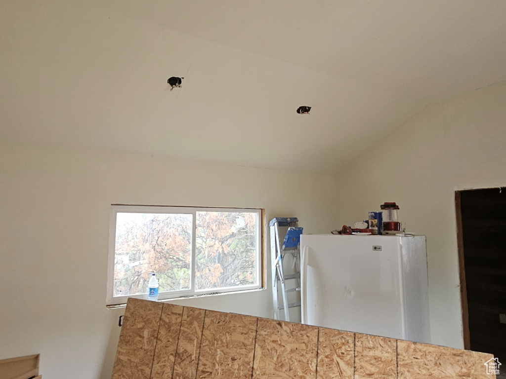 Kitchen featuring white refrigerator and vaulted ceiling