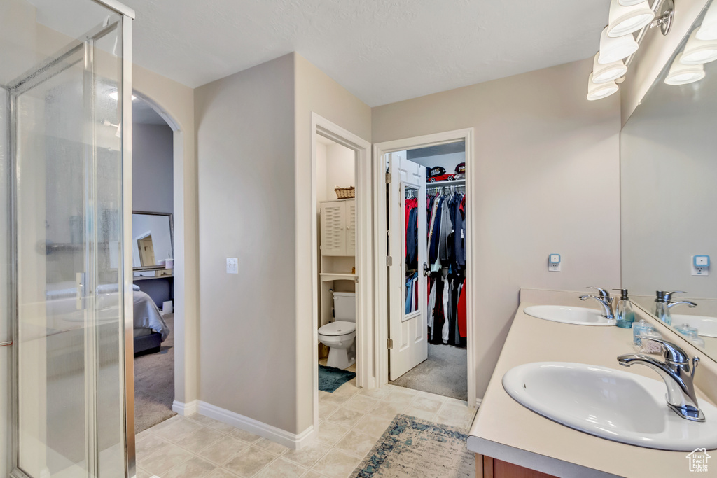 Bathroom with a shower with door, toilet, vanity, and tile patterned floors