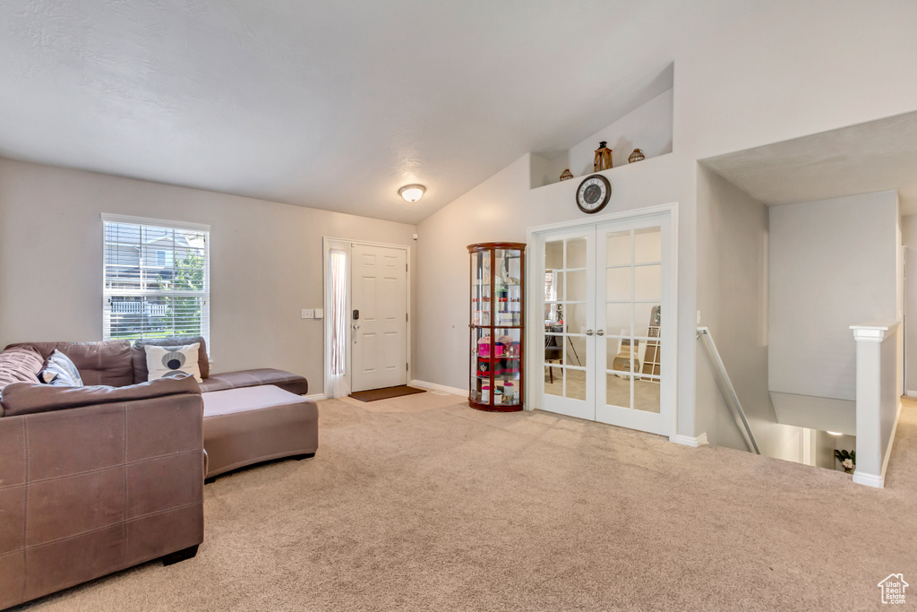 Carpeted living room featuring vaulted ceiling and french doors