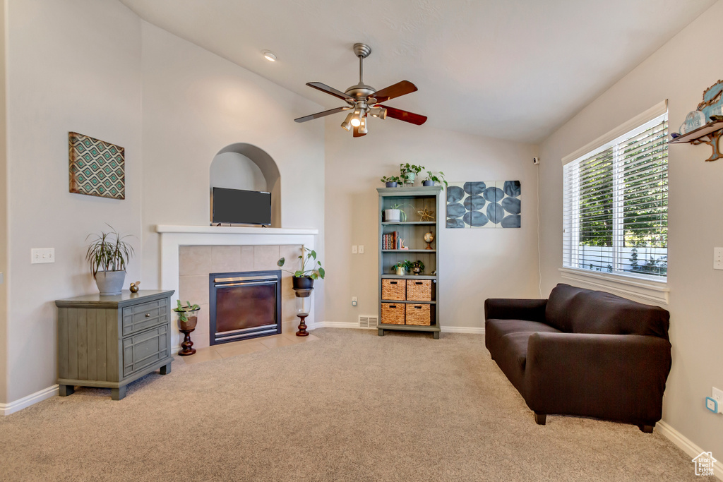 Carpeted living room featuring ceiling fan, a fireplace, and vaulted ceiling