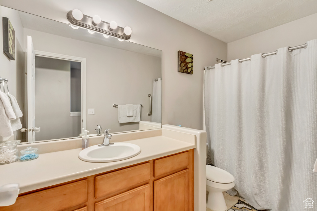 Bathroom featuring a shower with shower curtain, toilet, and vanity