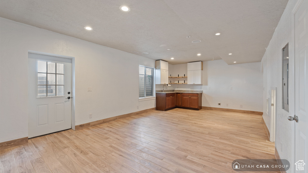 Unfurnished living room with sink and light wood-type flooring