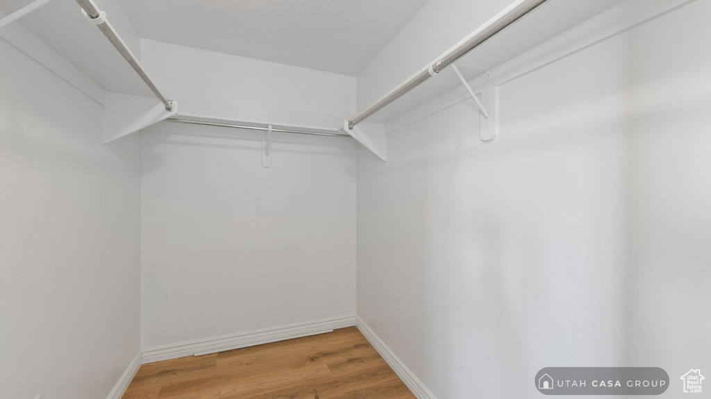 Walk in closet with light hardwood / wood-style flooring