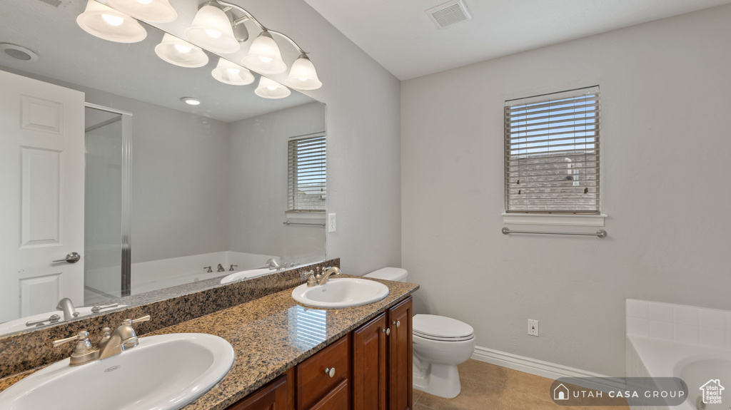 Bathroom featuring a washtub, tile patterned flooring, toilet, and vanity