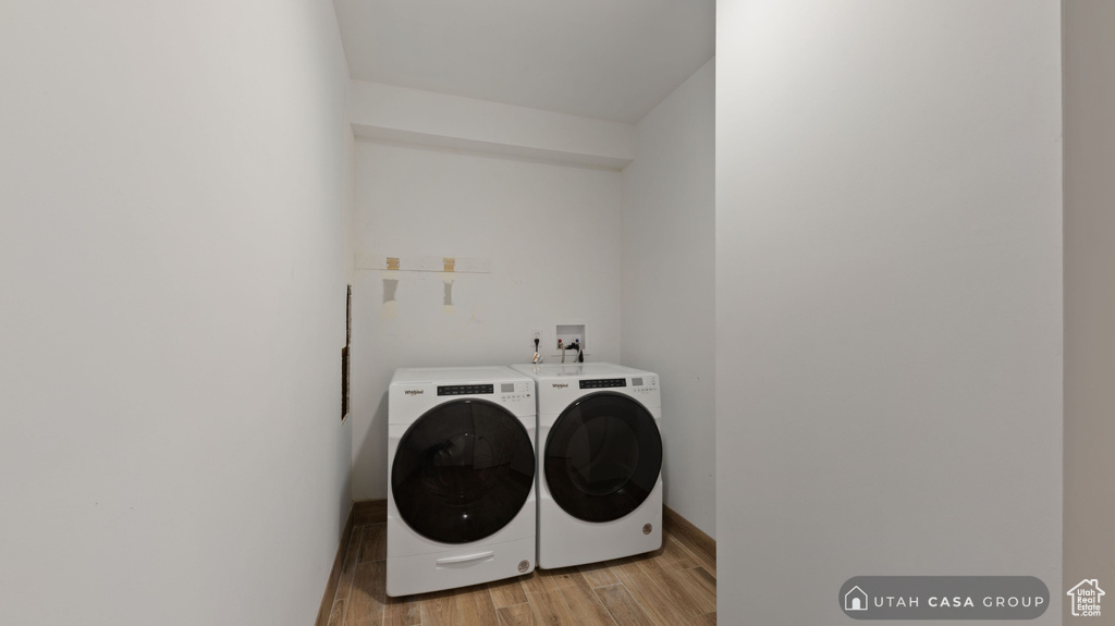 Washroom with washer and clothes dryer and light wood-type flooring