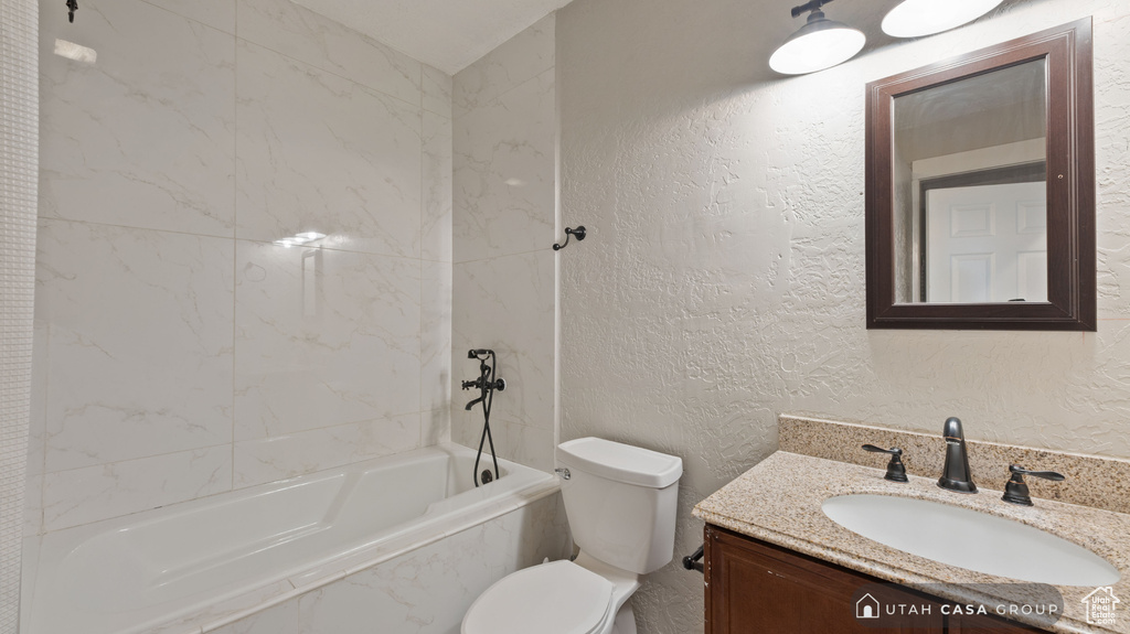 Full bathroom featuring toilet, tiled shower / bath, and vanity