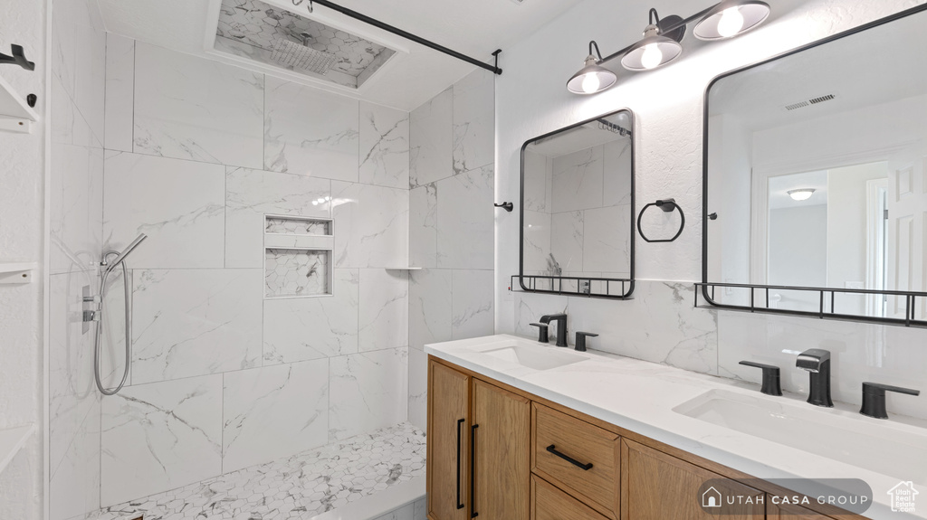 Bathroom featuring backsplash, tile walls, a tile shower, and vanity