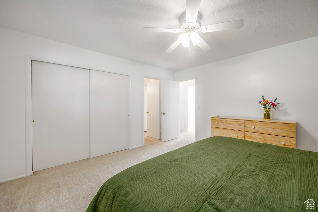 Unfurnished bedroom with light colored carpet, ceiling fan, and a closet