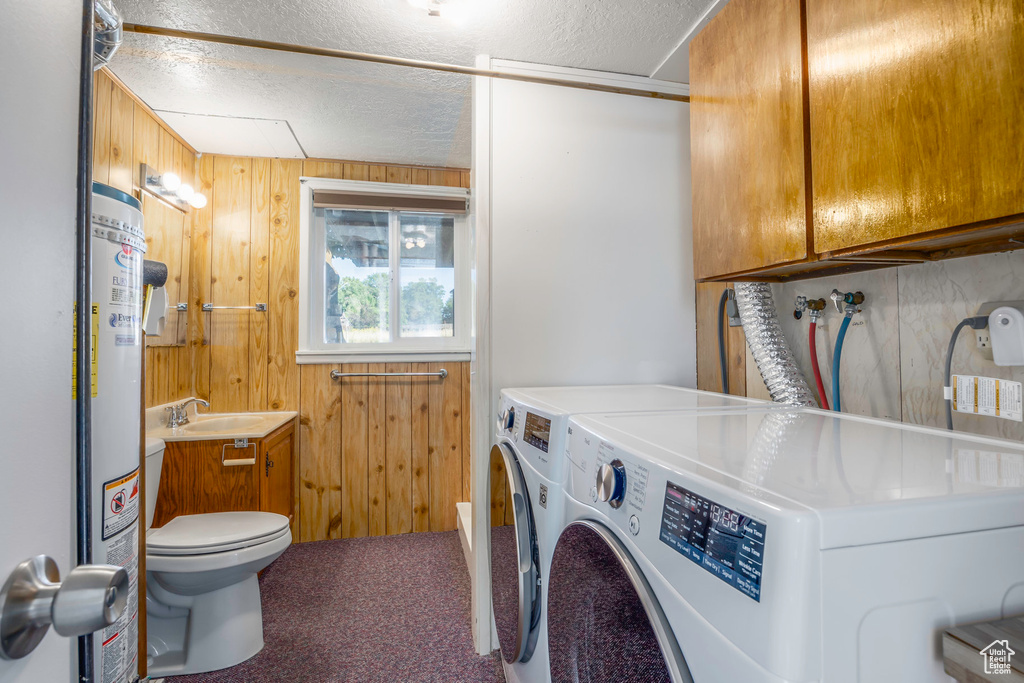 Washroom featuring wooden walls, washing machine and dryer, sink, carpet floors, and a textured ceiling