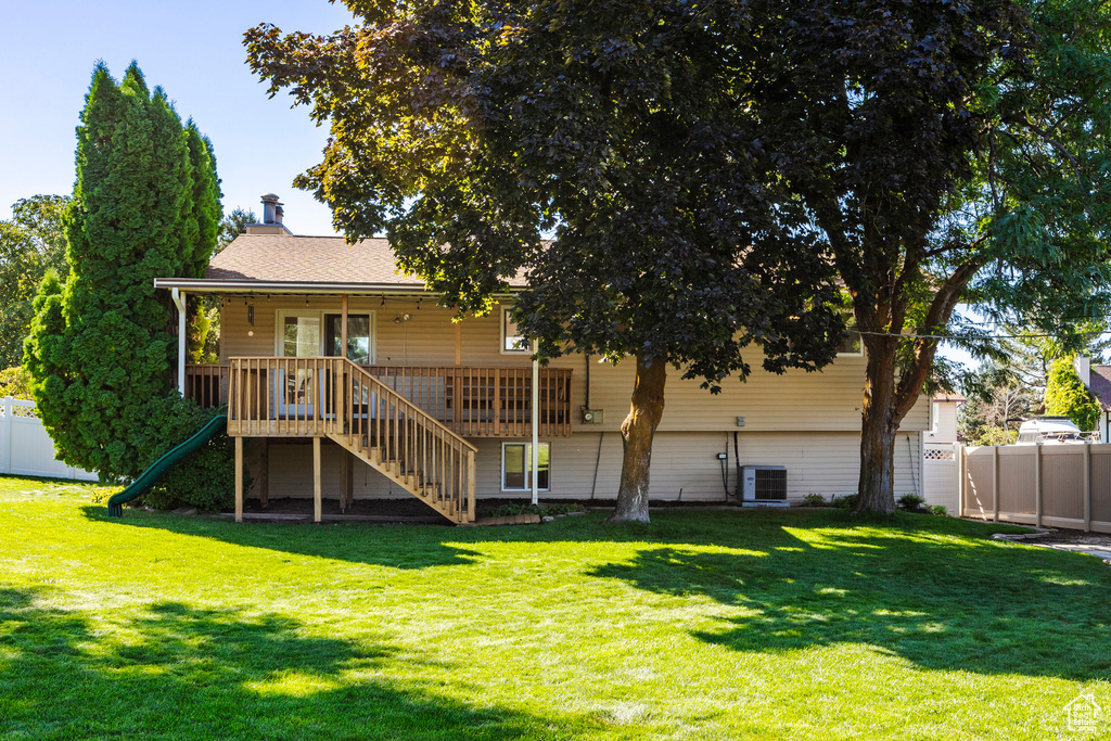 Back of house with central AC and a lawn