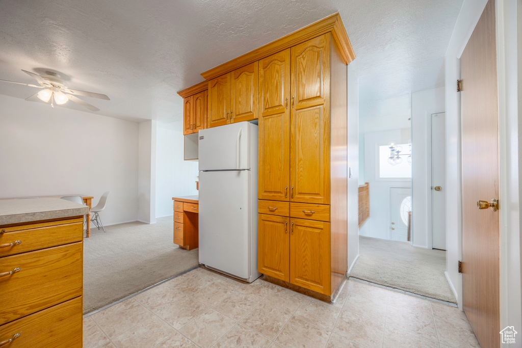 Kitchen with ceiling fan, white refrigerator, and light tile patterned flooring