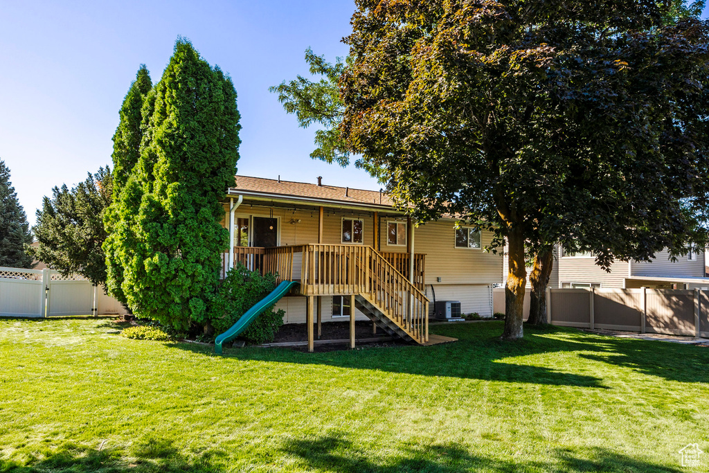 Rear view of house featuring cooling unit and a yard