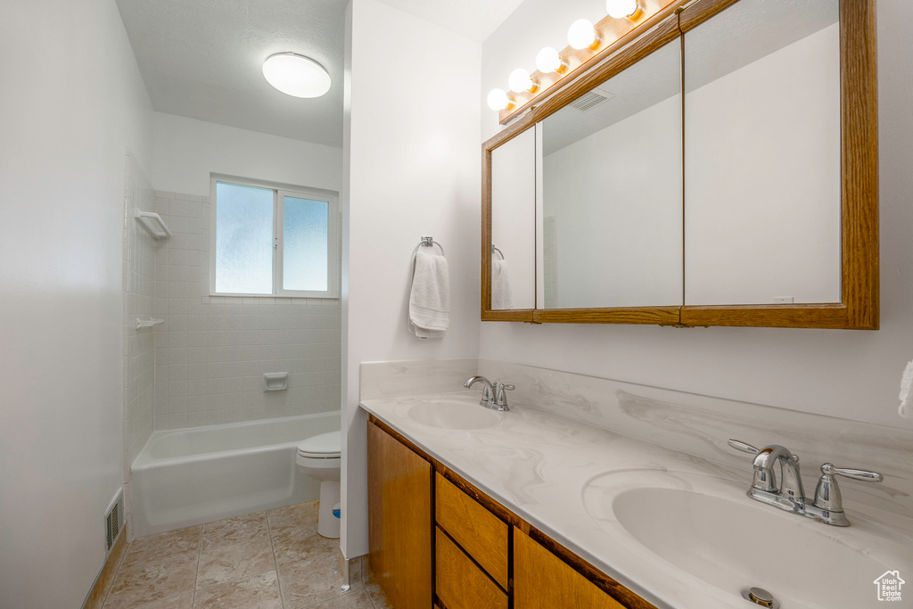 Full bathroom with tile patterned flooring, toilet, tiled shower / bath, and vanity