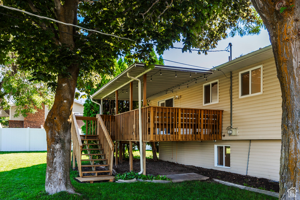 Back of house with a wooden deck and a lawn