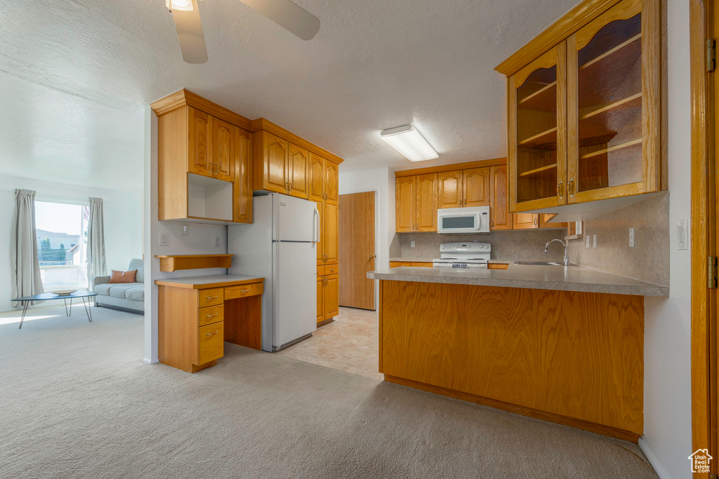 Kitchen featuring kitchen peninsula, light carpet, white appliances, and ceiling fan