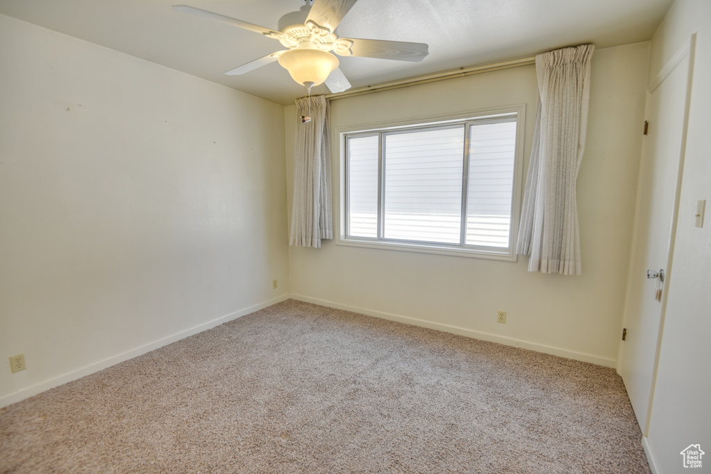 Empty room featuring ceiling fan and light carpet