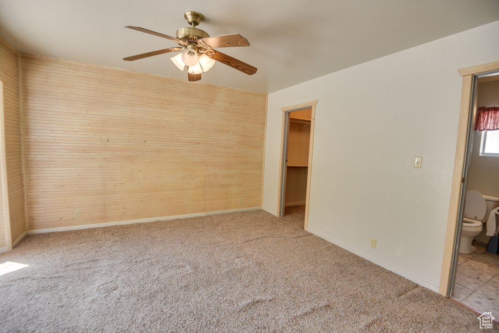 Unfurnished bedroom featuring a walk in closet, connected bathroom, and light carpet