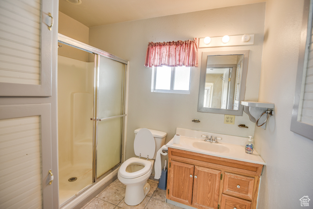 Bathroom with tile patterned flooring, a shower with shower door, toilet, and vanity