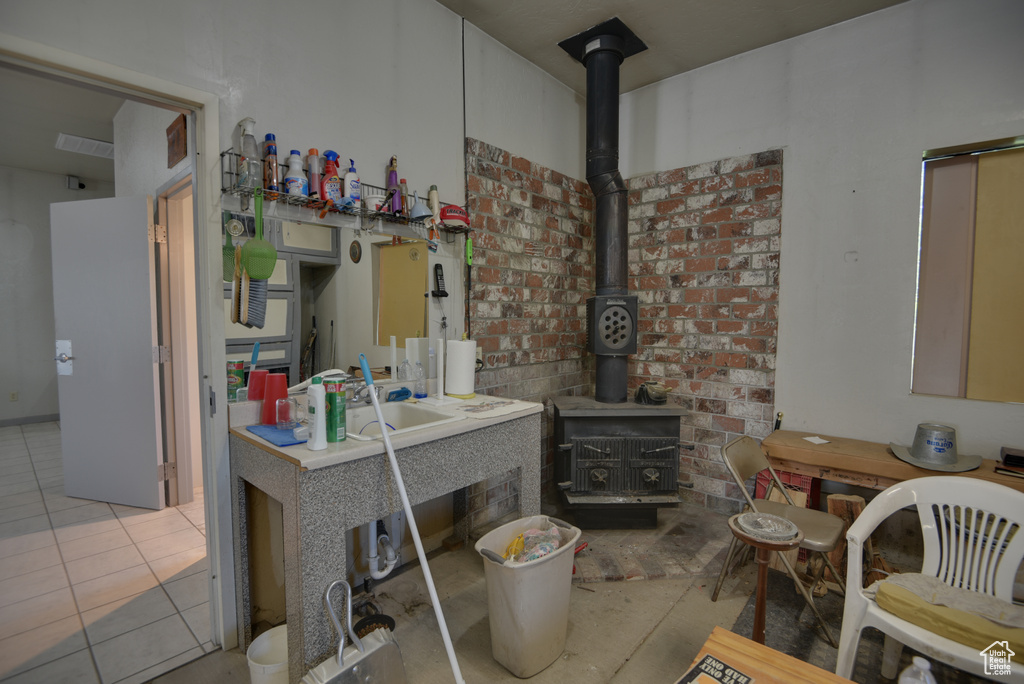 Interior space with sink, light tile patterned floors, and a wood stove