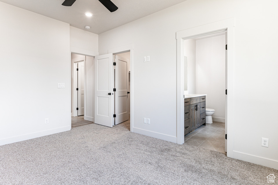 Unfurnished bedroom featuring ceiling fan, connected bathroom, and light carpet