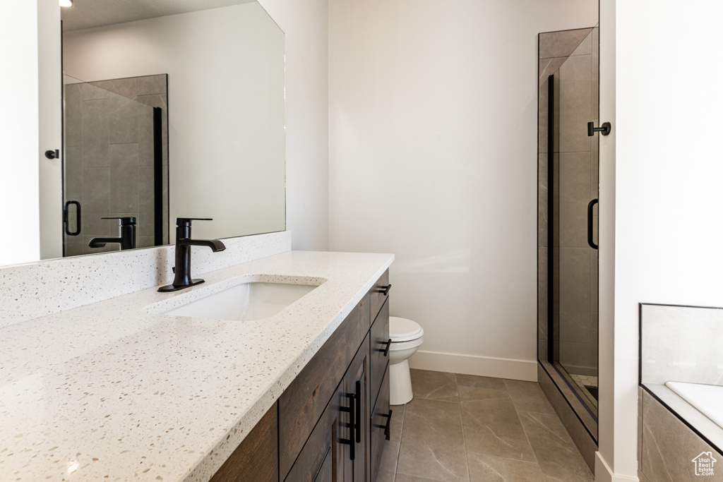 Bathroom featuring walk in shower, vanity, toilet, and tile patterned floors