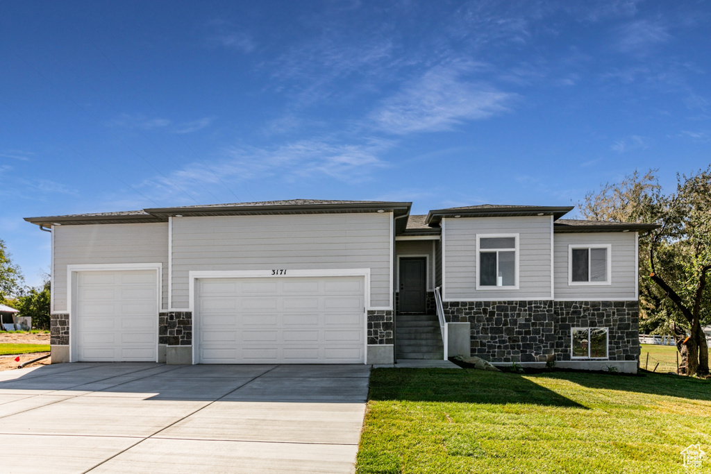 View of front of home with a garage and a front lawn