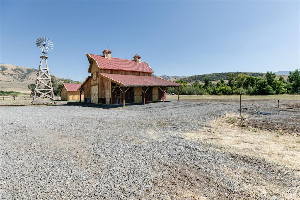 Rear view of property featuring a mountain view, an outdoor structure, and a rural view