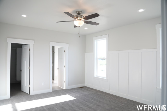 Unfurnished bedroom with connected bathroom, light carpet, and ceiling fan