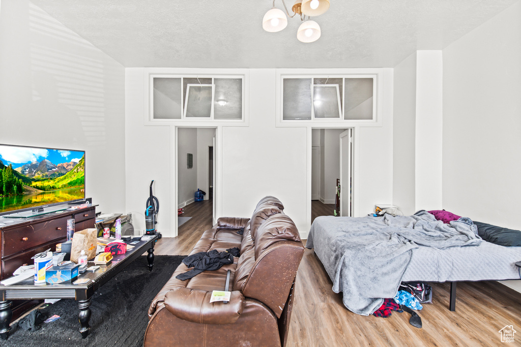 Bedroom with a textured ceiling, light hardwood / wood-style flooring, and a notable chandelier