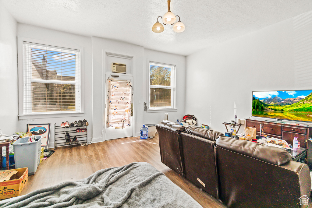 Living room with hardwood / wood-style flooring, a wall mounted air conditioner, and a textured ceiling