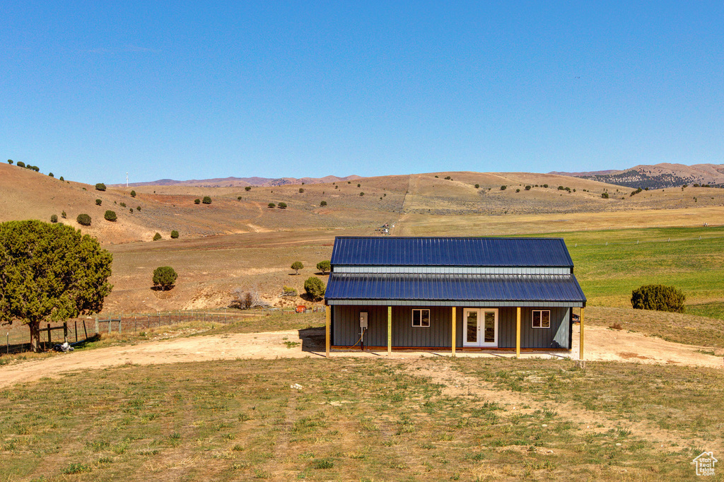 View of front of home featuring a rural view, an outdoor structure, and a mountain view