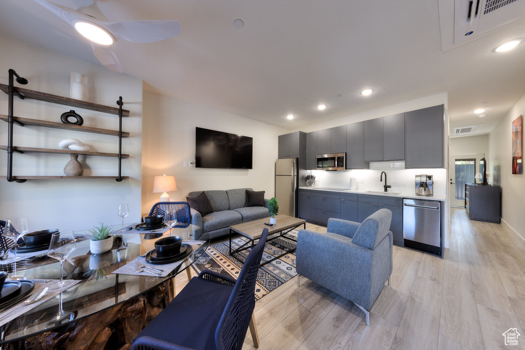 Living room with light wood-type flooring, sink, and ceiling fan