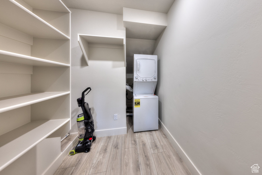 Laundry room featuring light hardwood / wood-style floors and stacked washer / drying machine