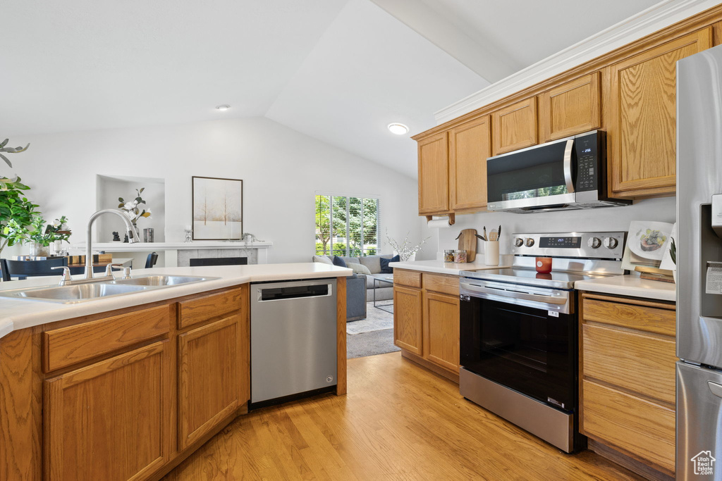 Kitchen with lofted ceiling, light wood-type flooring, sink, and appliances with stainless steel finishes