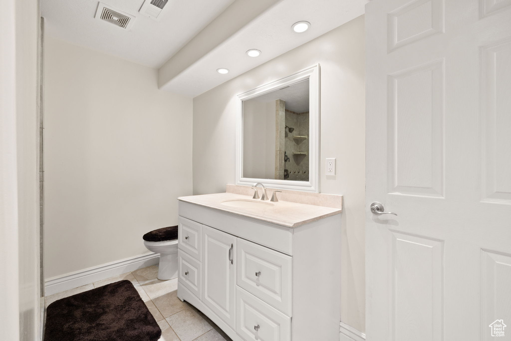 Bathroom featuring vanity, toilet, a shower, and tile patterned flooring