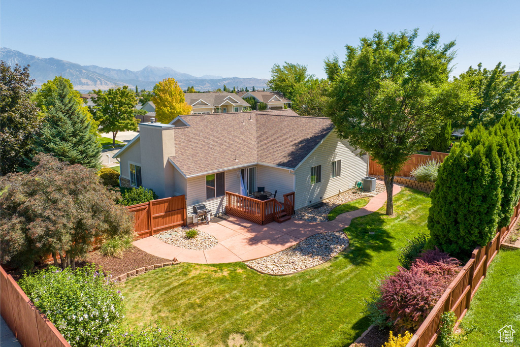 Exterior space with a mountain view, a lawn, a patio area, and central AC unit