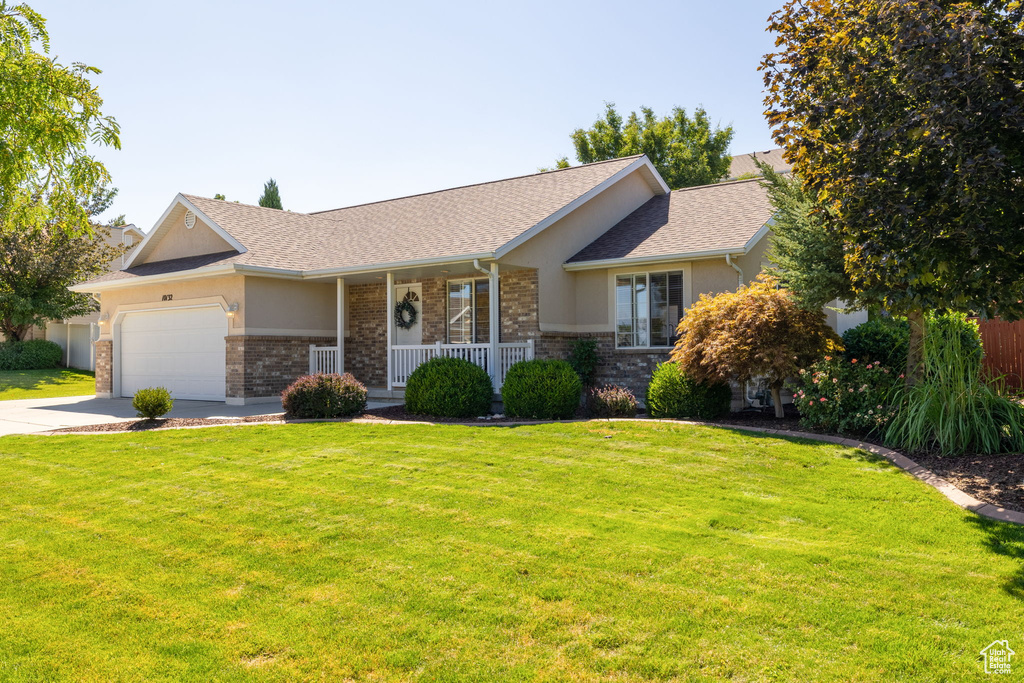 Ranch-style home featuring a garage, a porch, and a front lawn