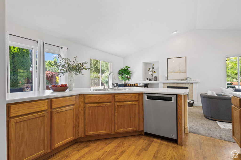 Kitchen with dishwasher, vaulted ceiling, light hardwood / wood-style flooring, sink, and kitchen peninsula